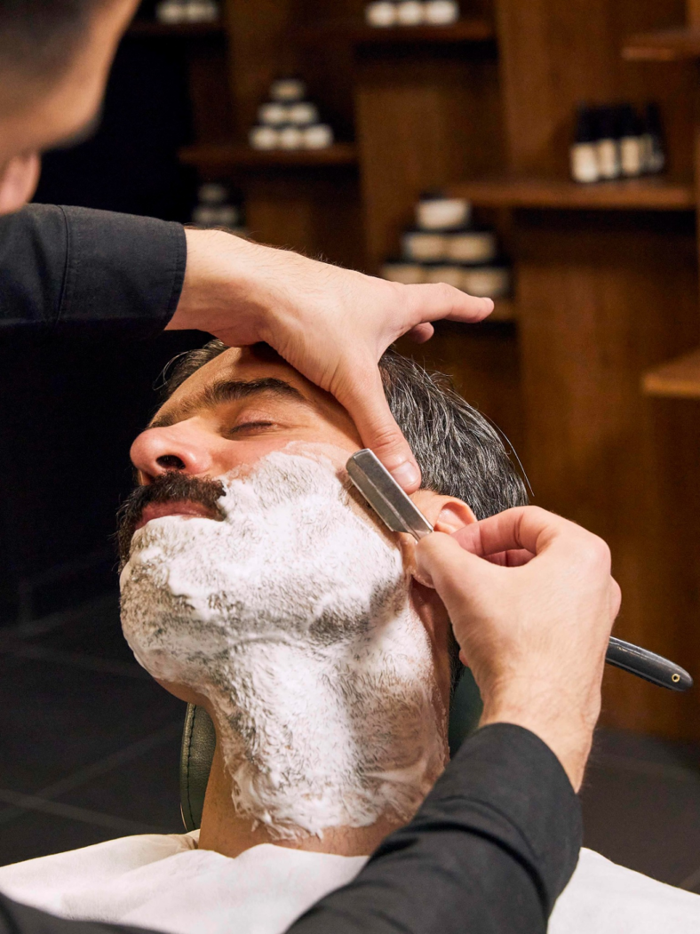 A barber shaves a mans face at Adam Grooming Atelier in Harrods