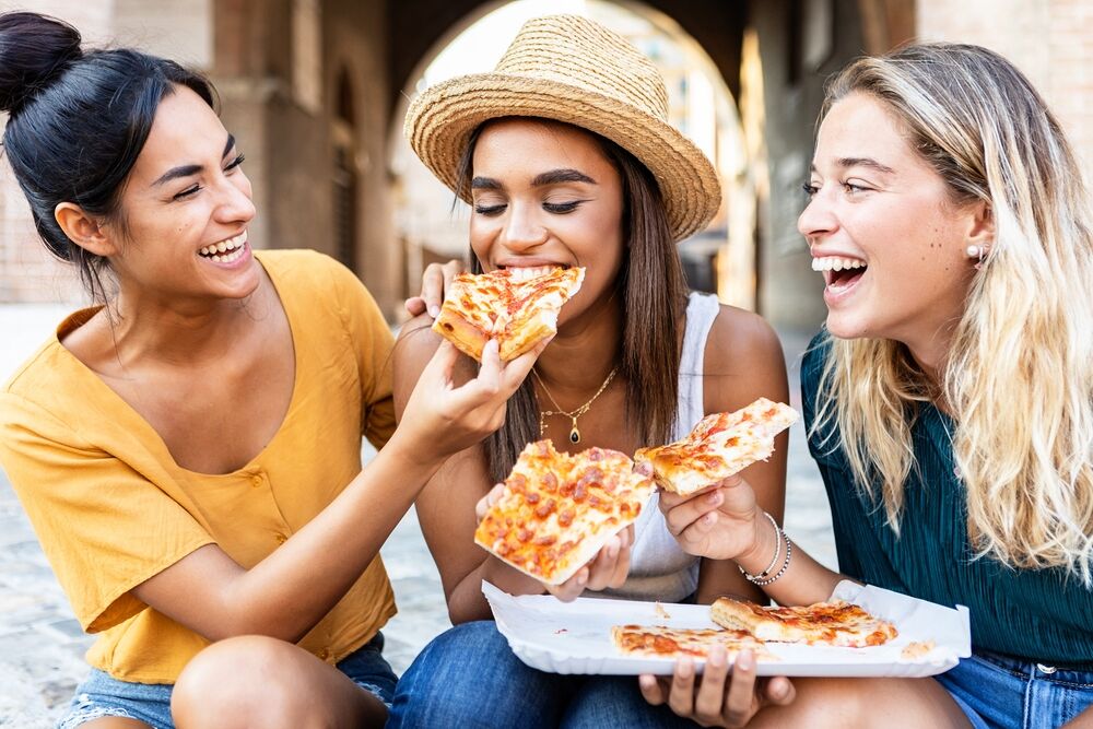Three women eating pizza in Milan
