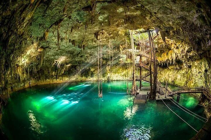 Underground Cenote with blue water and light shining through the cavern roof