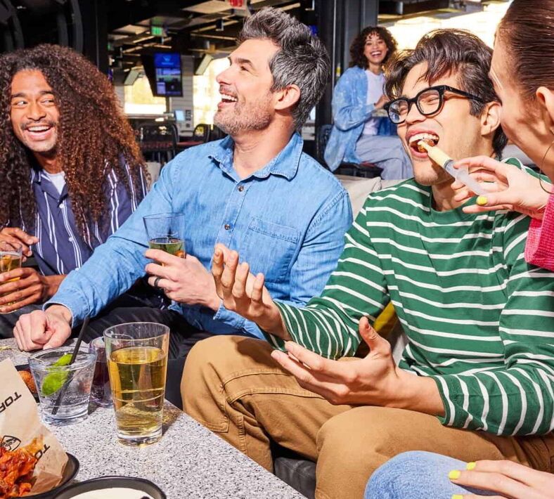 Guests laughing and enjoy drinks and food at Topgolf at MGM Grand.