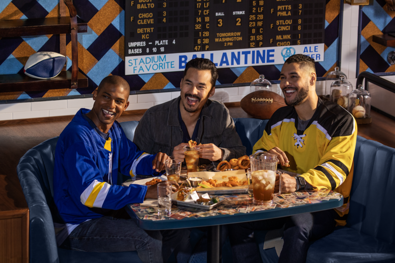 Thee men wearing sports jerseys enjoy food at drinks before a football game at MGM Resorts, Las Vegas.