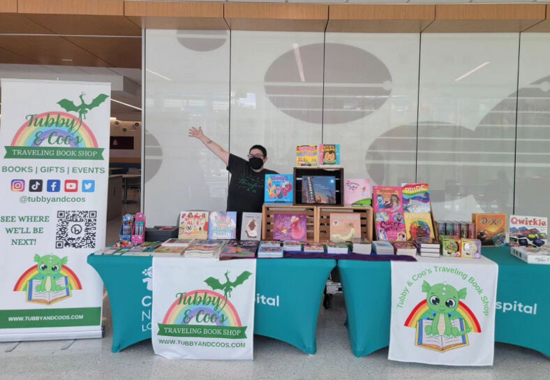 An image of the owner of Tubby & Coos traveling book shop selling books at an event. 