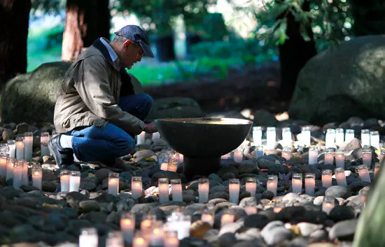 A visitor reflects on a memorial at the National AIDS Memorial Grove in San Francisco
