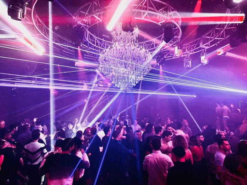 A packed dance floor of South Beach Houston. A large chandelier and laser lights light up the floor. Photo via South Beach Houston. 