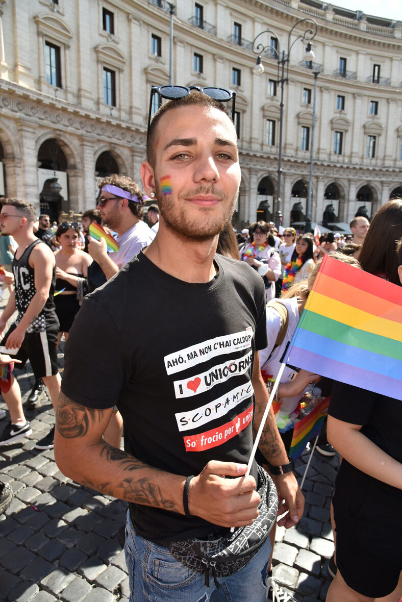 Man in Rome during Pride holds a rainbow flag.
