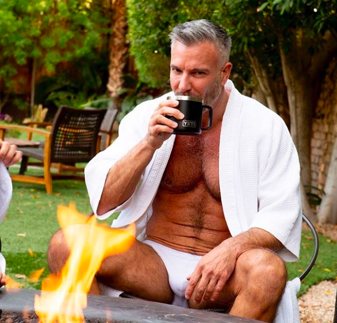 Palm Springs hotels man by a fire pit sips out of a Yeti cup.