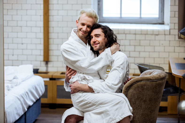 two men in bathrobes inside a hotel room