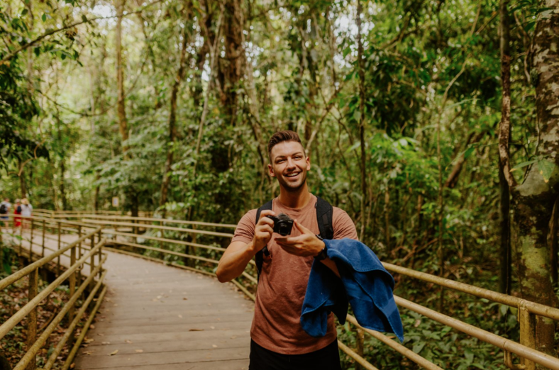 Man in a jungle holding a camera.
