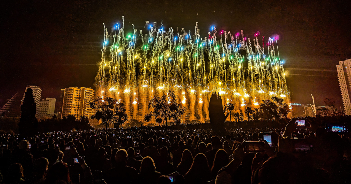 Yellow, green, blue, and purple fireworks stream into the sky during the Fallas festival in Valencia, Spain.