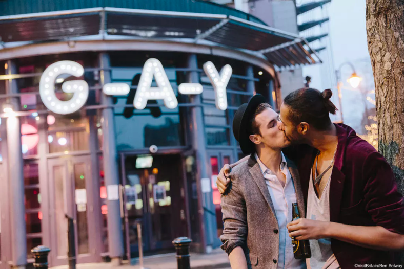 Gay couple standing outside G-A-Y Bar in Manchester. 