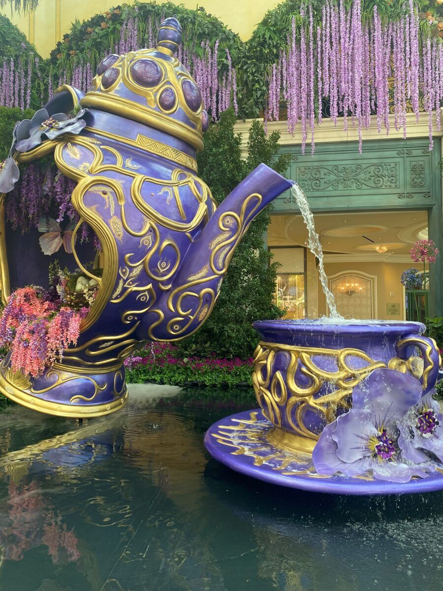 A giant purple tea pot fountain pours water into a massive tea cup. 