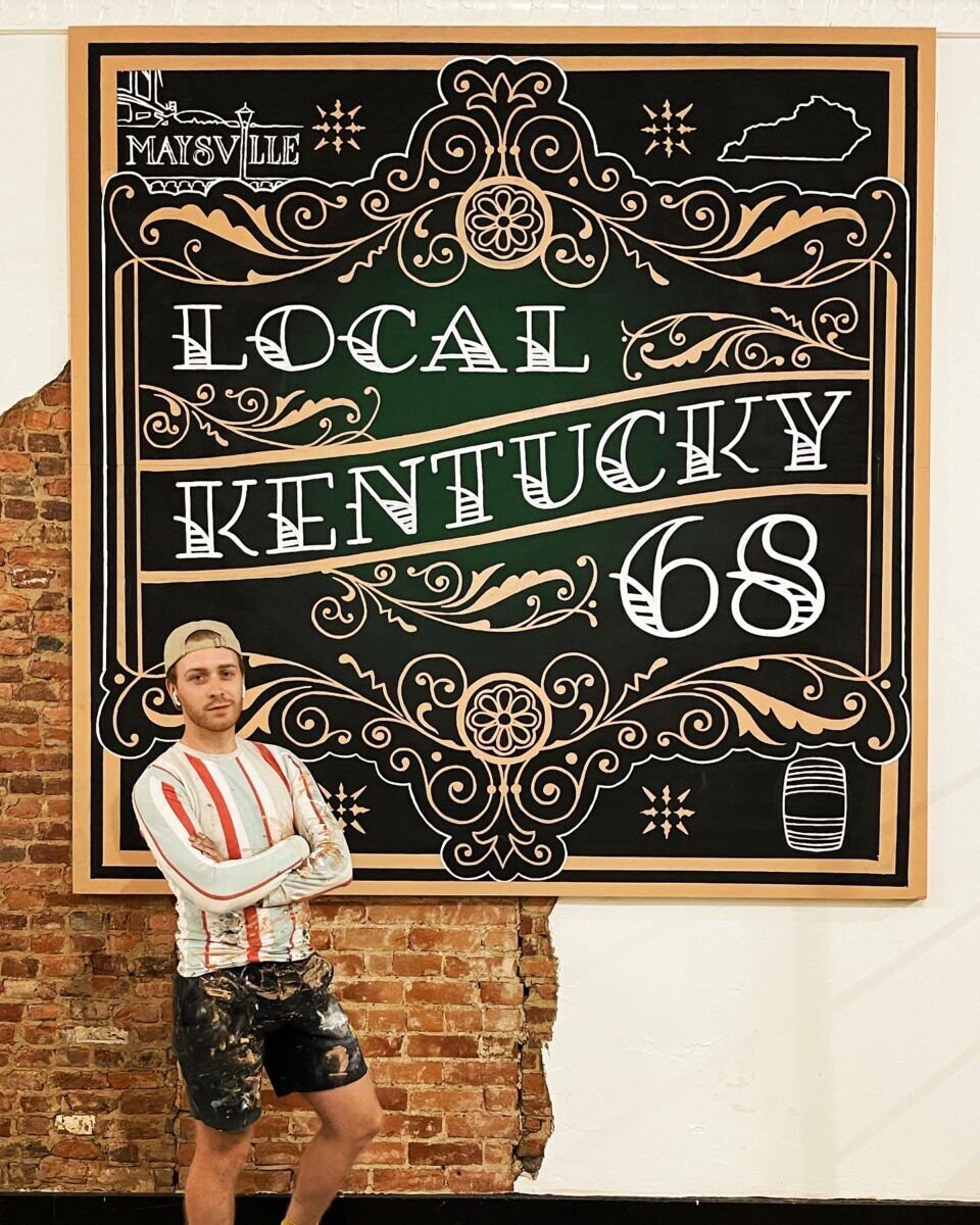 Caudill poses in front of a mural painted for Local Kentucky 68 artists' market in Maysville.