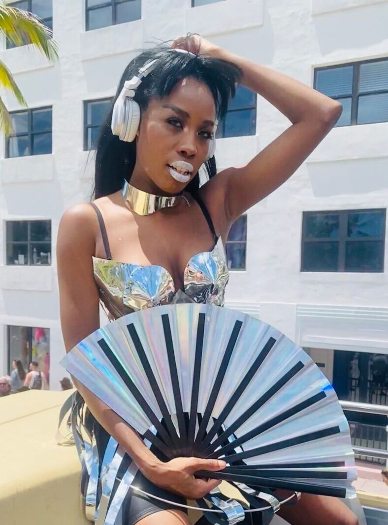 DJ Latrice flaunting her metallic futuristic aesthetic a top a float in the Miami Beach Pride Parade.
