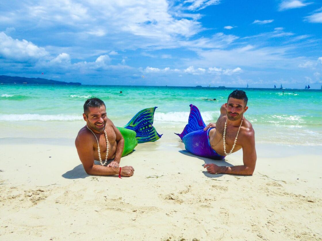 Stefan and Seby dressed as mermaids and lying on a beach in the Philippines.