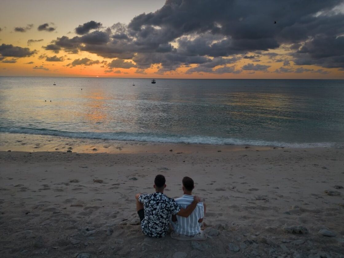 Stefan and Seby sit on the beach watching the sunset.