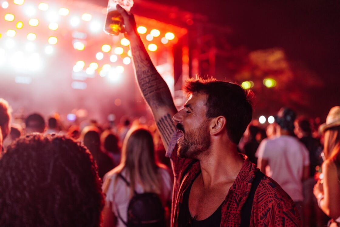 A man holds a beer and shouts during a music festival