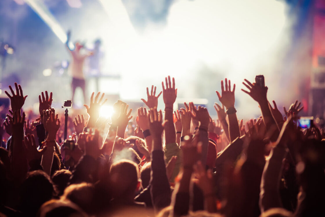 A crowd holds their hands in the air during a musical performance