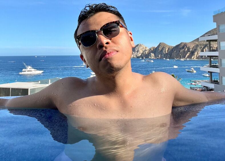 Uriel stretches out at the edge of Corazon Cabo's infinity pool with the ocean in the background.