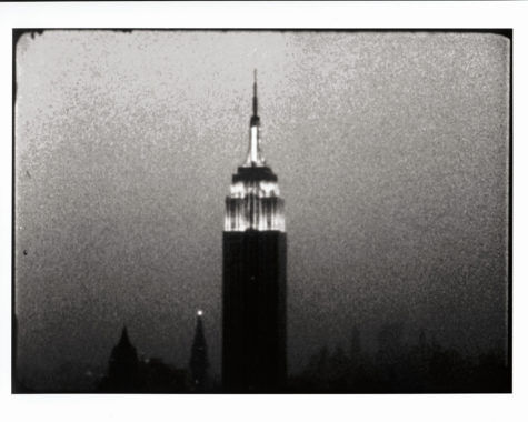 A black-and-white shot from Warhol's 1964 short film Empire, showing the Empire State Building lit up at night.