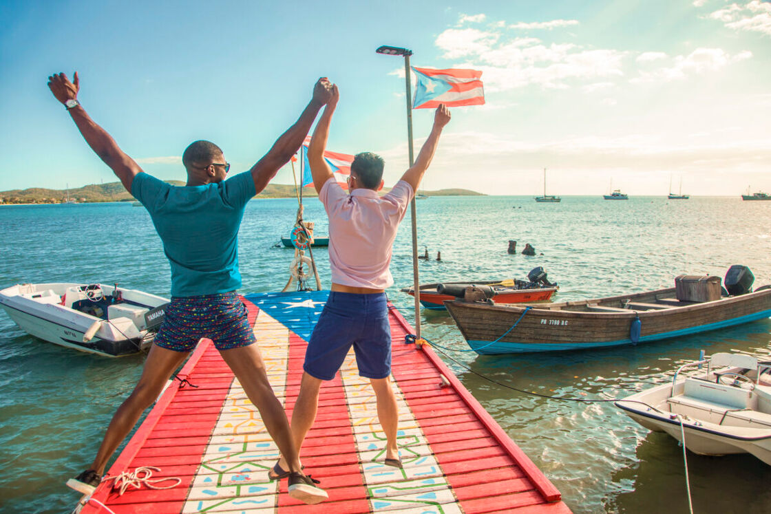 A gay couple on a pier painted with the Puerto Rican flag.