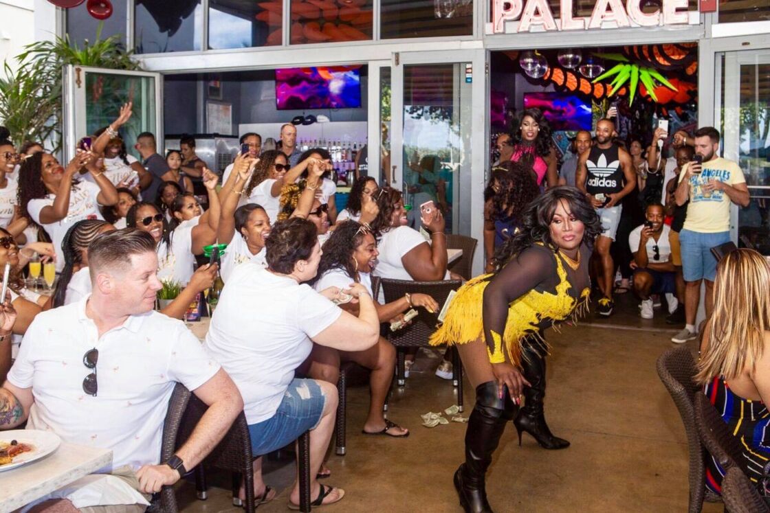 A drag queen twerks in front of an admiring audience on the outside patio