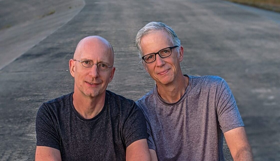 The author, Brent Hartinger, and his husband, Michael Jensen, pose in a street for a selfie.