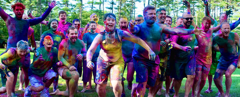 A group of participants covered in colorful paint at 'Camp' Camp, an adult LGBTQ+ summer camp