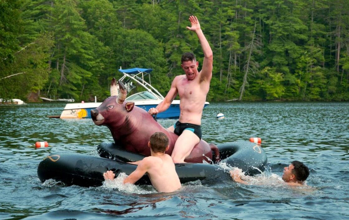 Adult LGBTQ+ summer camp attendees play in a lake at 'Camp' Camp.