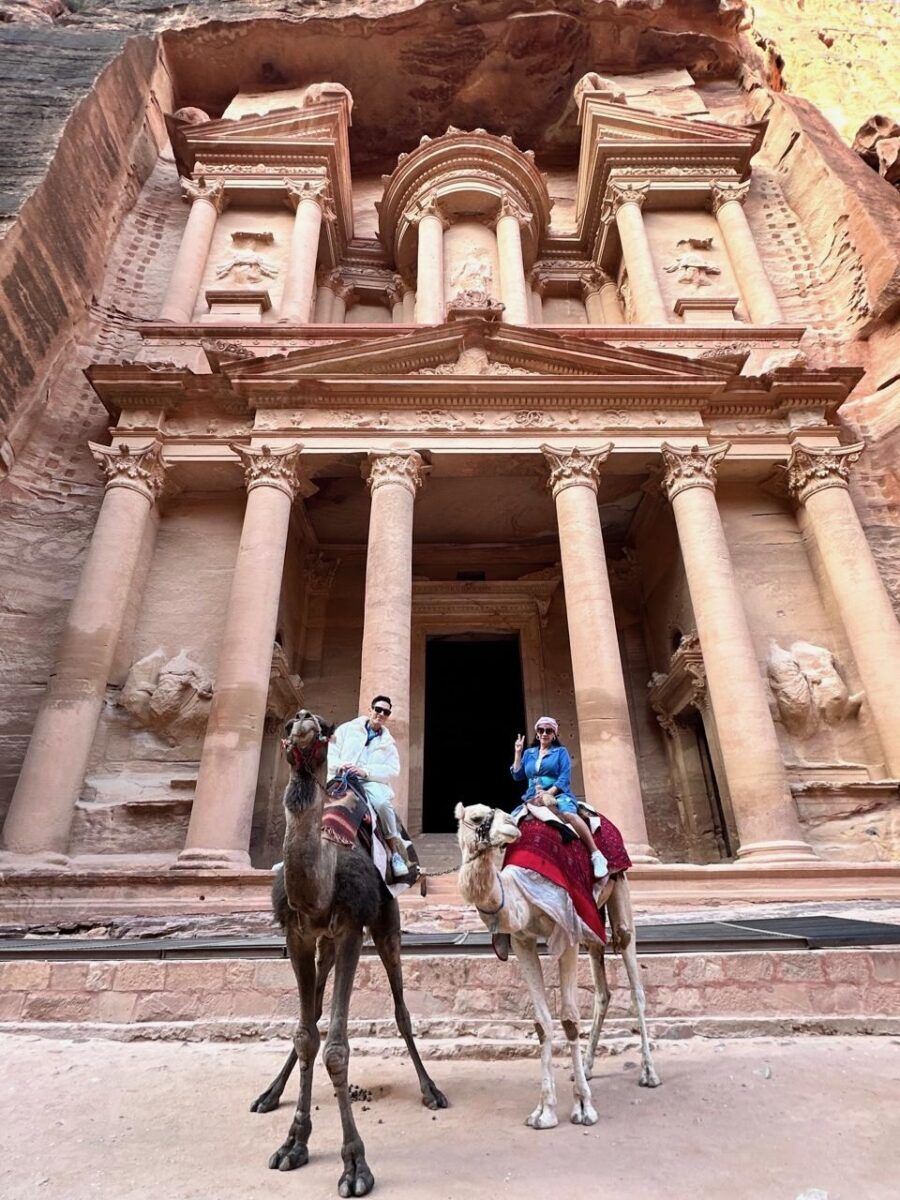 Crysthian Mancera and his mom, Patricia, sit astride camels in front of Petra.