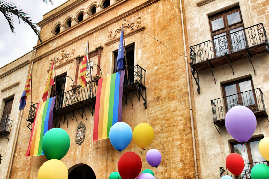 Rainbow flags and balloons hanging from the balcony of the town hall in Elche, Alicante, Spain.