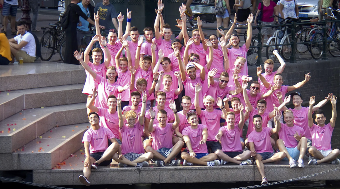 A group of teens in pink shirts sitting at homomonument.