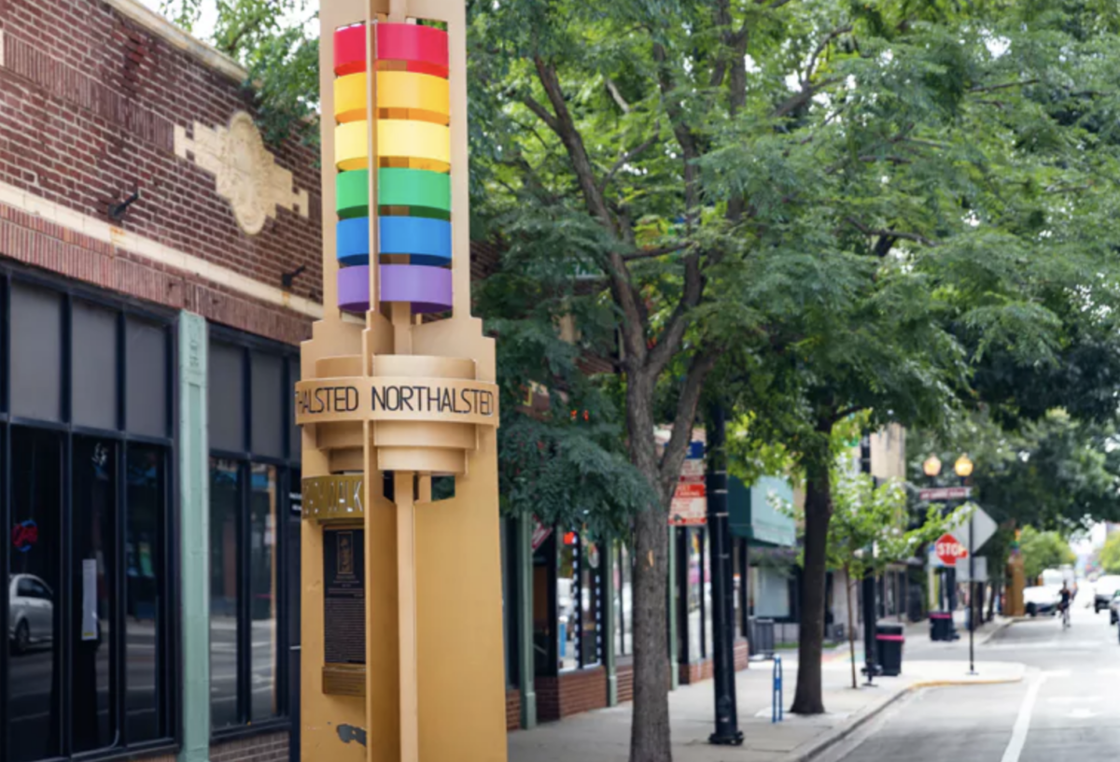 A gold signpost with the rainbow flag at the top marks the Northalsted neighborhood in Chicago.