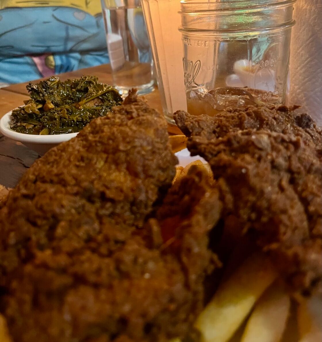 Collard greens, fried fish, Old Bay french fries and sweet tea sit on a table at Blaxicocina.