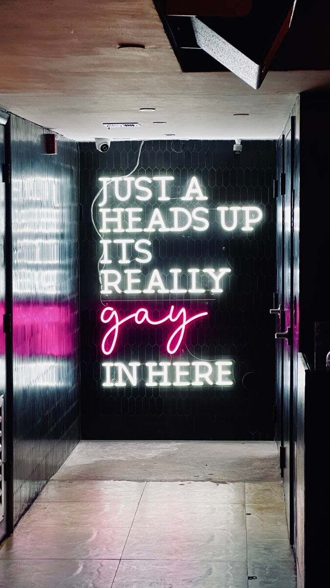 A neon sign from inside the venue that reads, "Just a heads up. Its really gay in here."