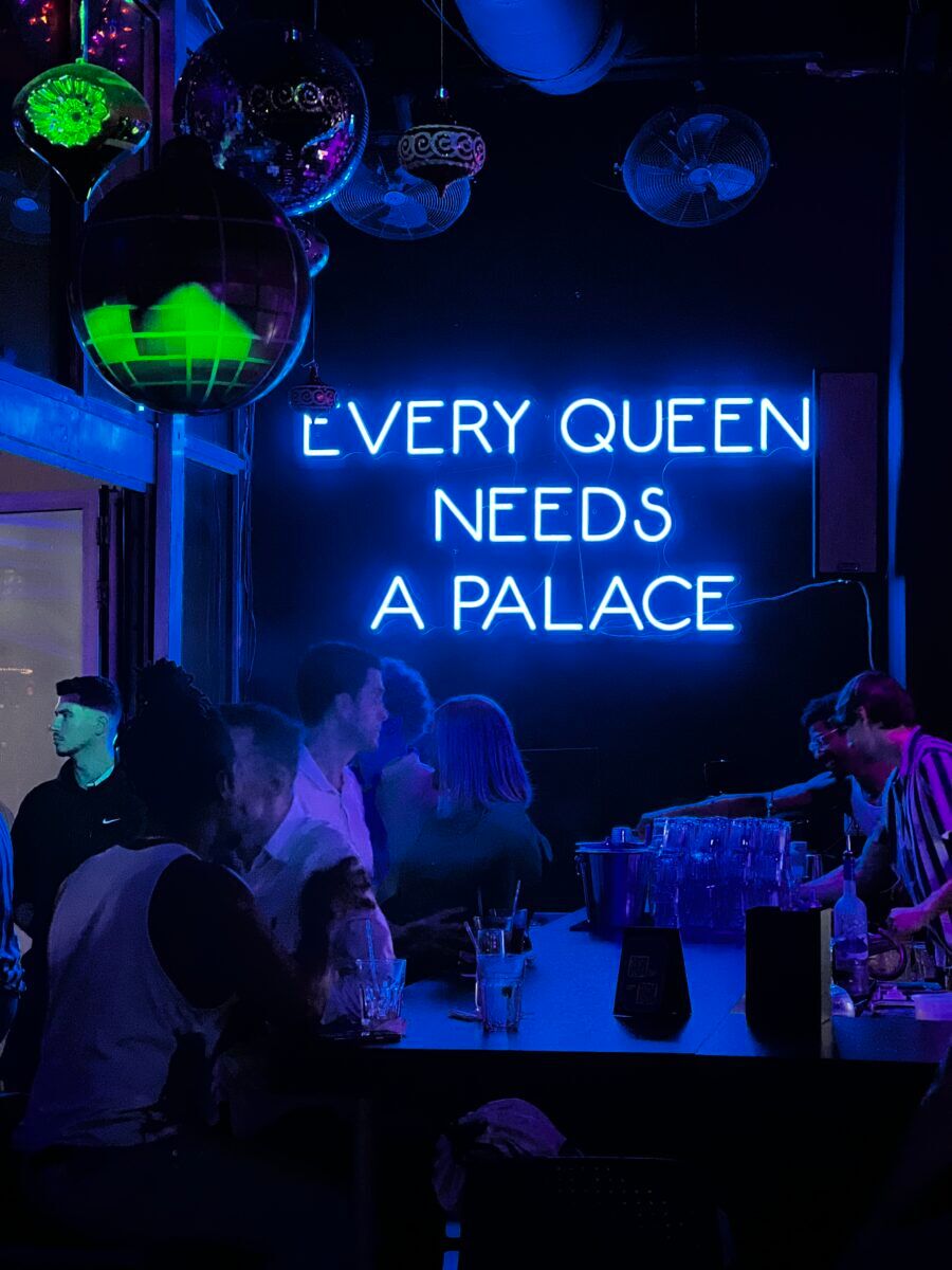 A neon sign from inside the venue that reads, "Every queen needs a palace."