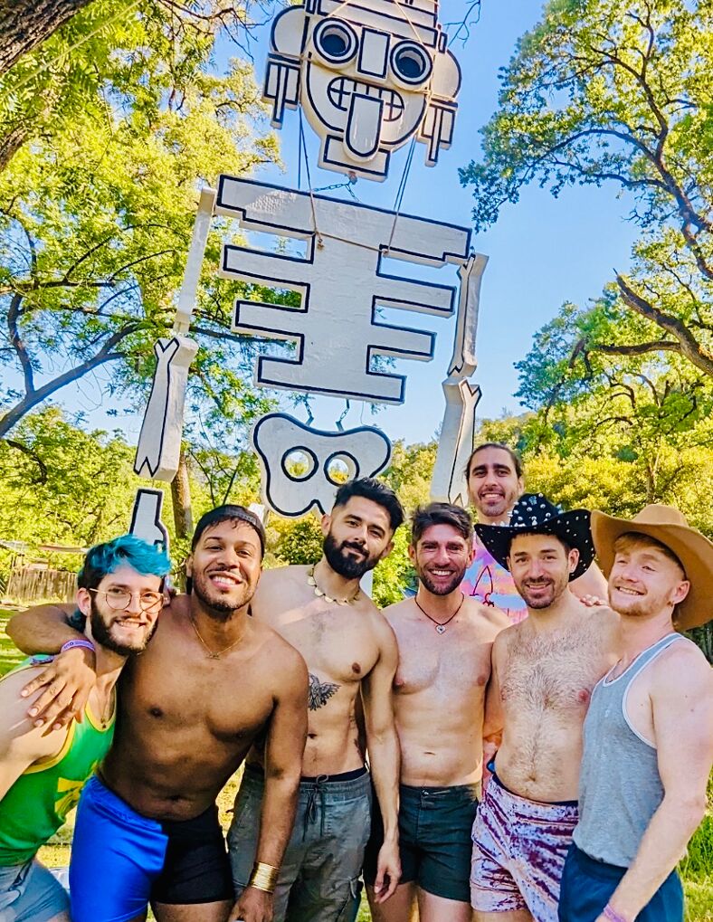 Adult campers pose in front of a skeleton sculpture at Something Queer, a camp for the adult LGBTQ+ community