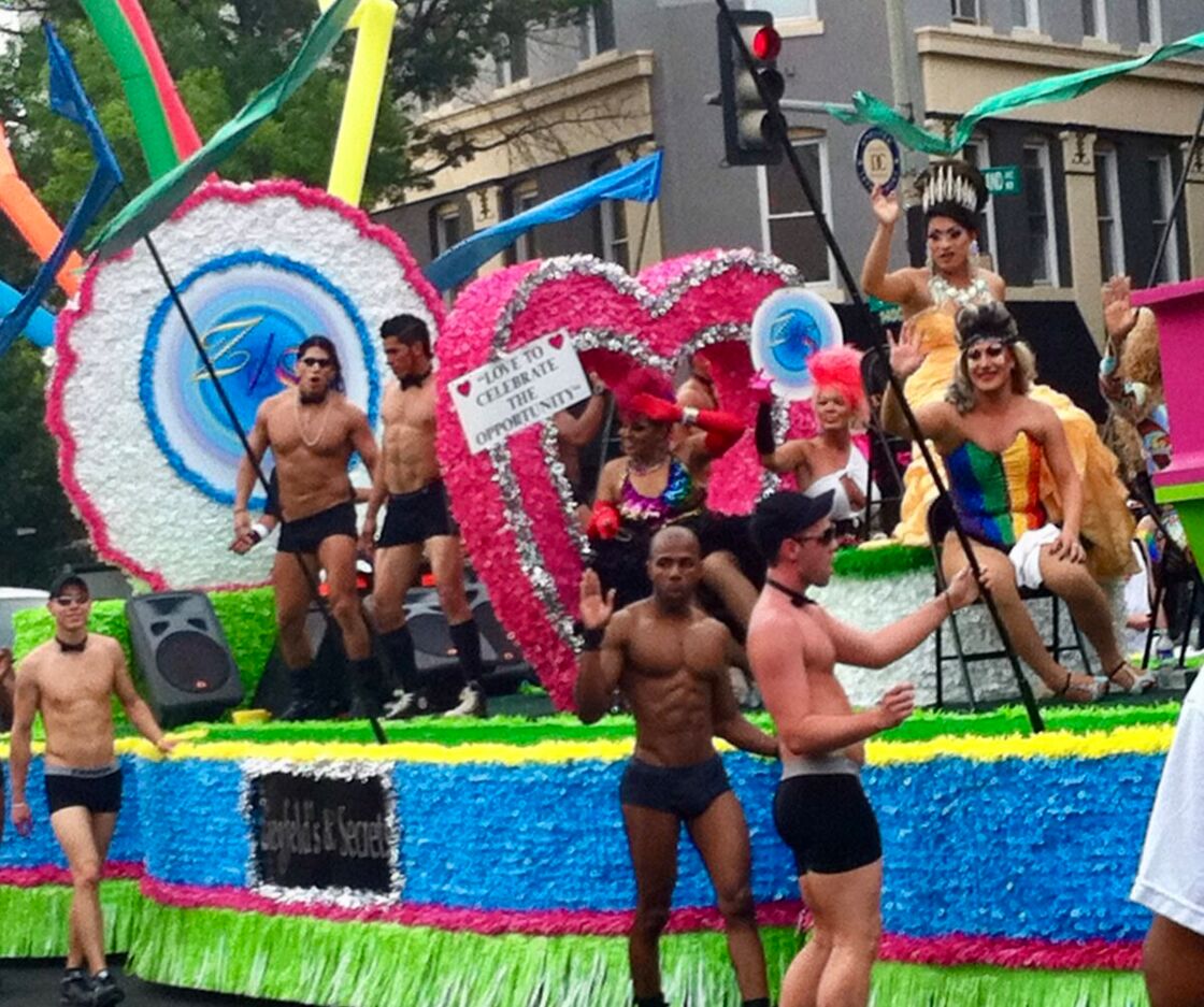 Pride revelers walk beside and ride a float for Ziegfeld's and Secrets bars.