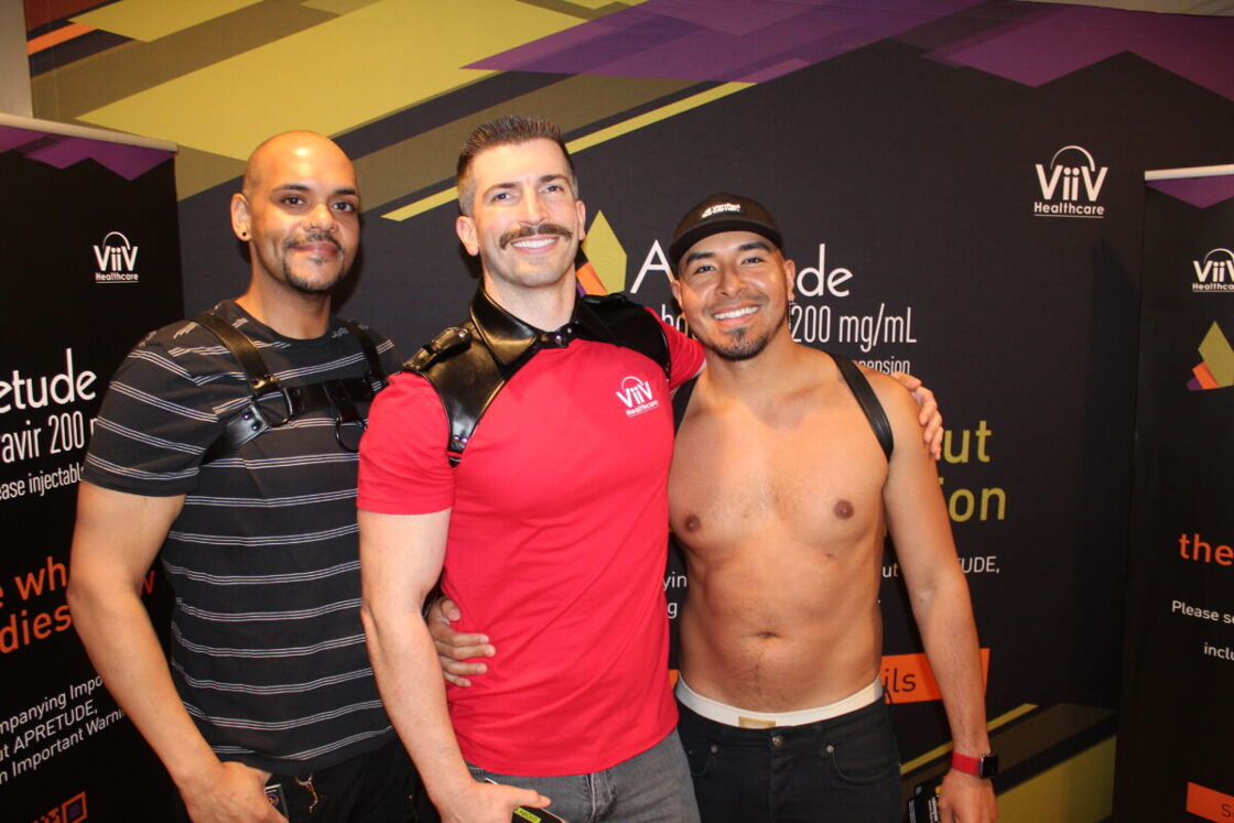 Three men pose for the camera at a booth for IML.