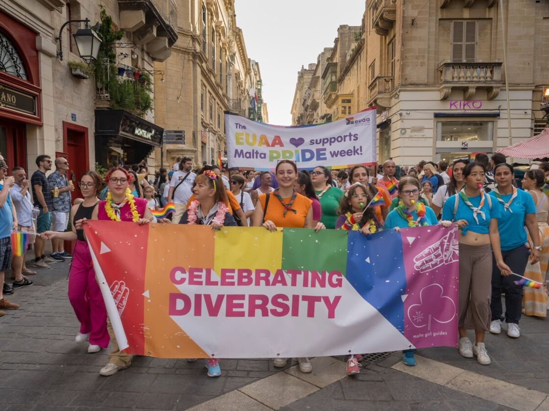 a group of mostly female-presenting people celebrating Malta Pride Week in 2022 holding a rainbow banner that says "celebrating diversity"