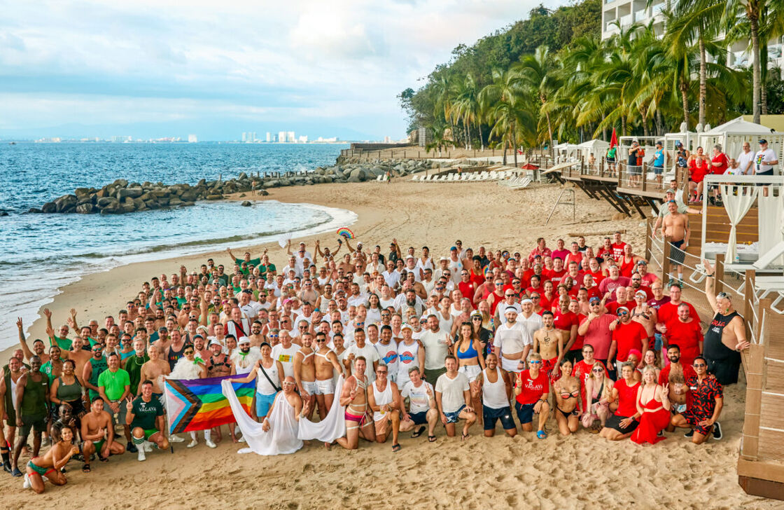 A large diverse group of LGBTQ+ travelers on the beach at VACAYA's 2024 Puerto Vallarta resort getaway.