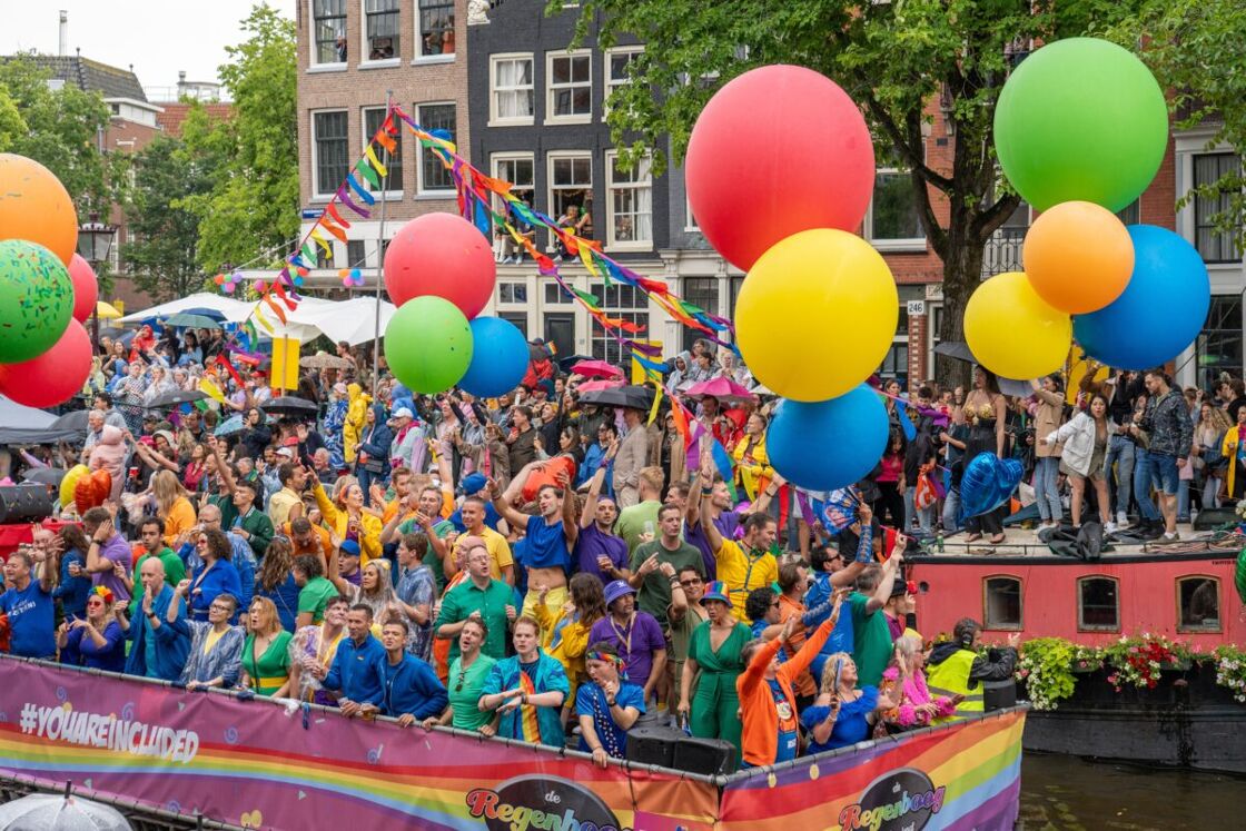 A group of people on a rainbow boat celebrating the Pride festival in Amsterdam. 