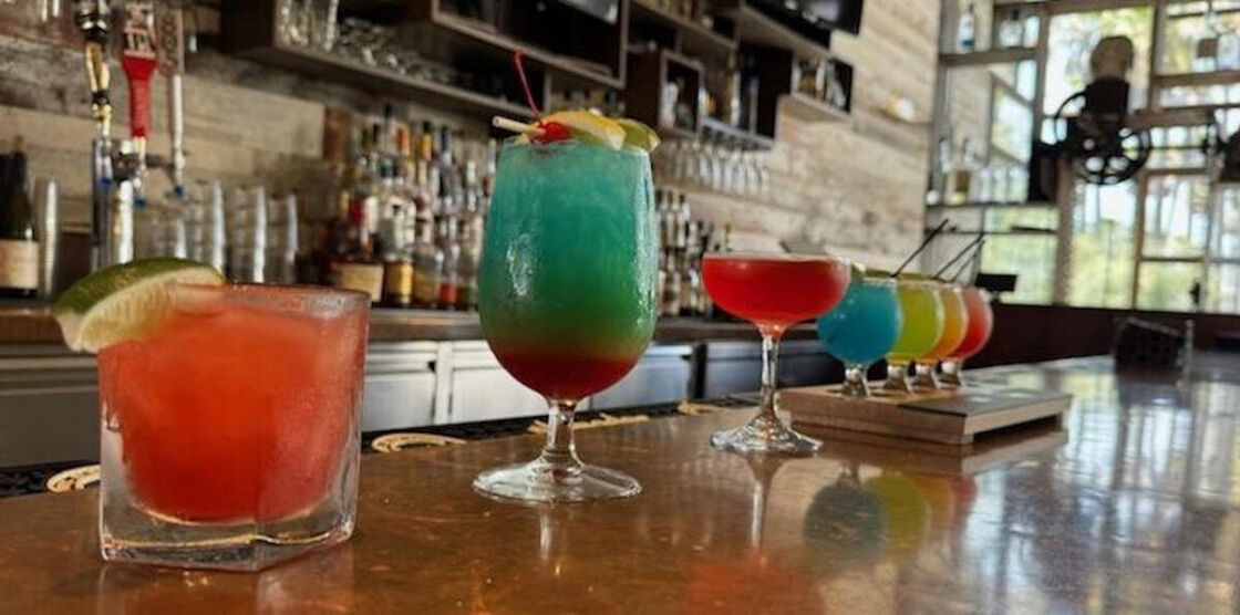 An array of colorful cocktails on a shiny bar. Photo via Hotel Maya