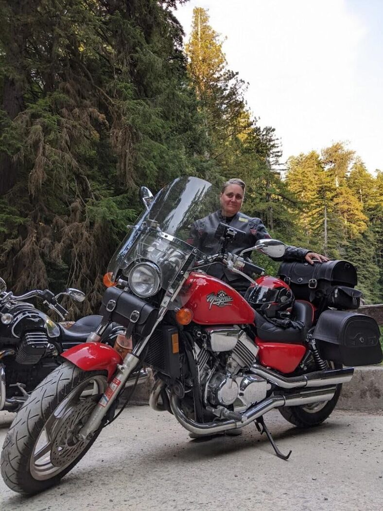 Kate Brown stands behind her motorcycle