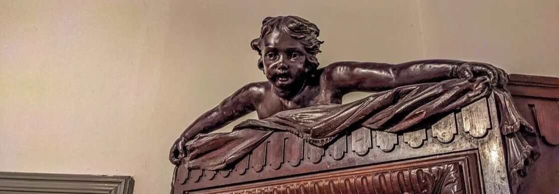 A cherub looks down from the top of a cabinet