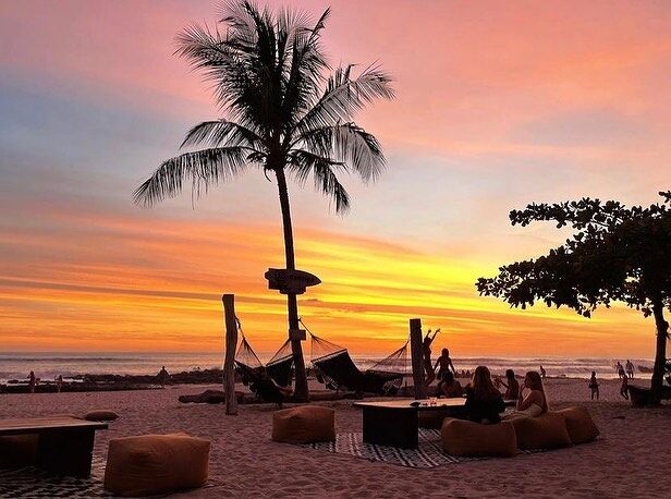 A beach with hammocks at sunset with the Costa Rican coastline behind. Photo via Hotel Nantipa