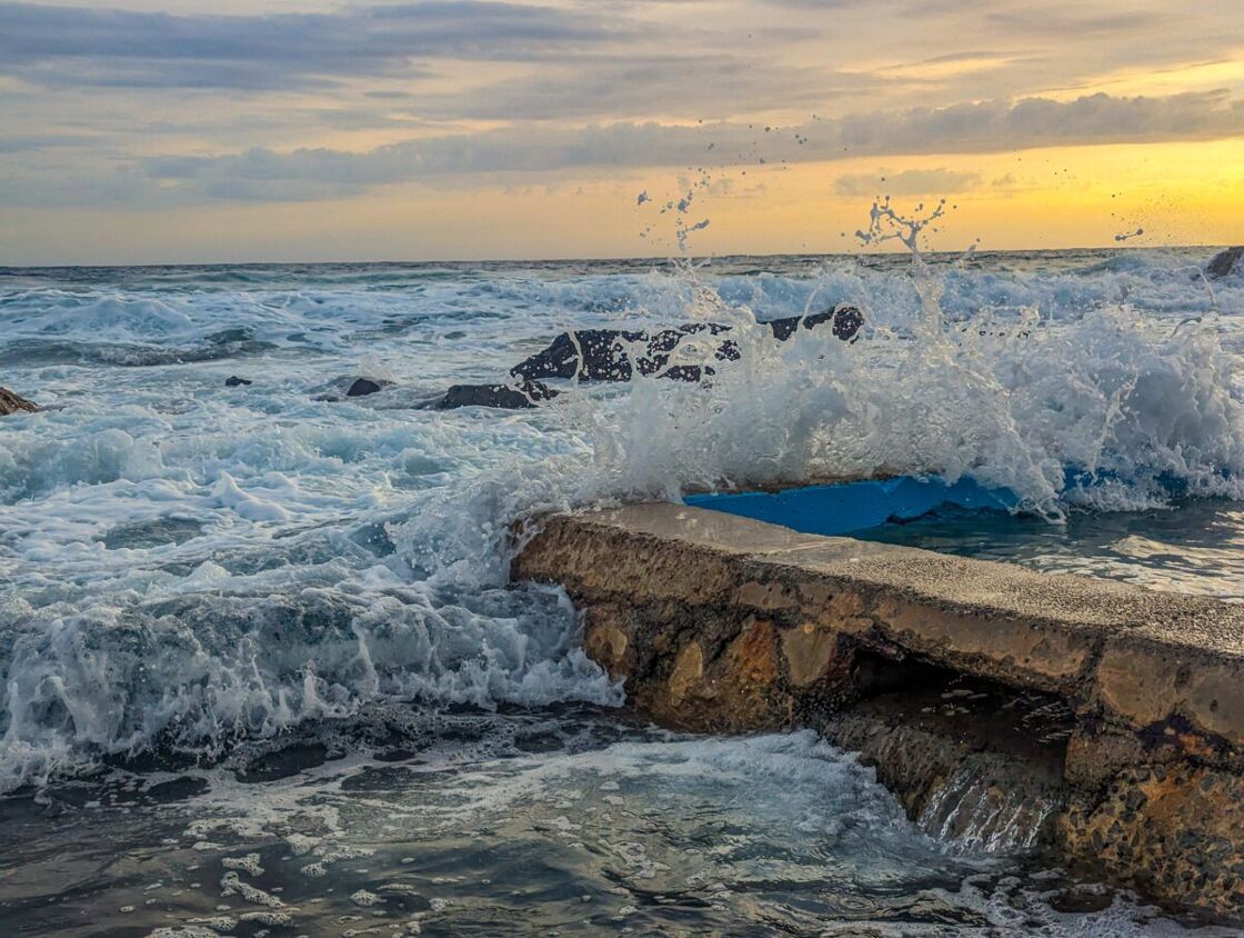 A wave breacking against the side of a rock pool. Waves crashing over the edge of a rock pool