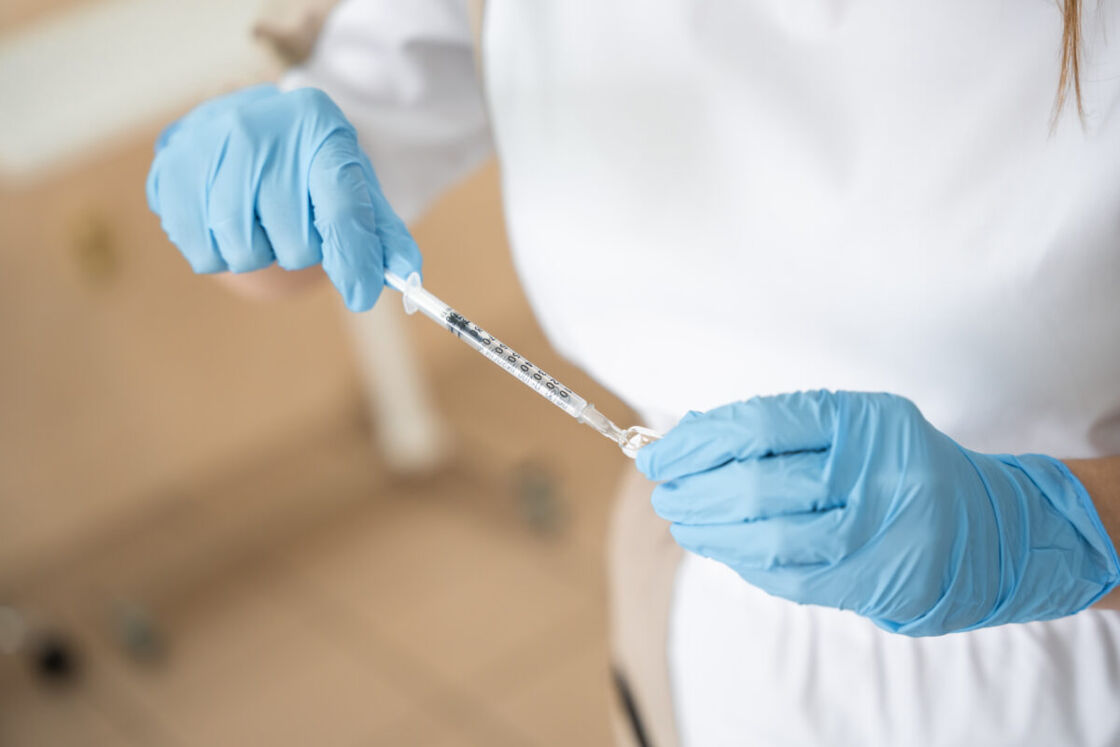 A medical professional holds a syringe