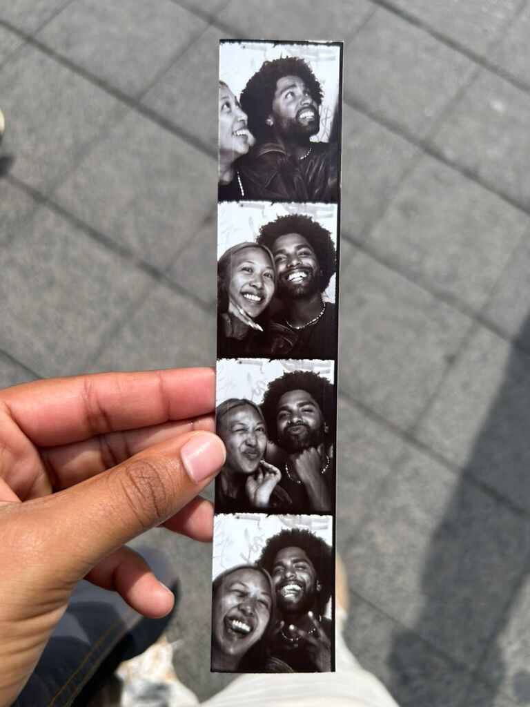 A strip of photos from a photobooth machine showing a Black woman and man smiling and laughing.