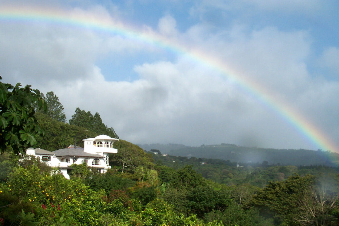 Jungle view with Finca Rosa Blanca nestled amongst the trees with a rainbow overhead. Photo via Finca Rosa Blanca