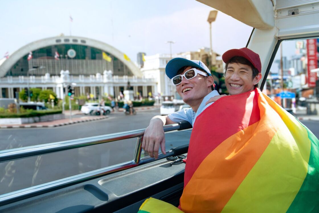 A gay couple wrapped in a rainbow flag traveling on a bus in Bangkok, Thailand